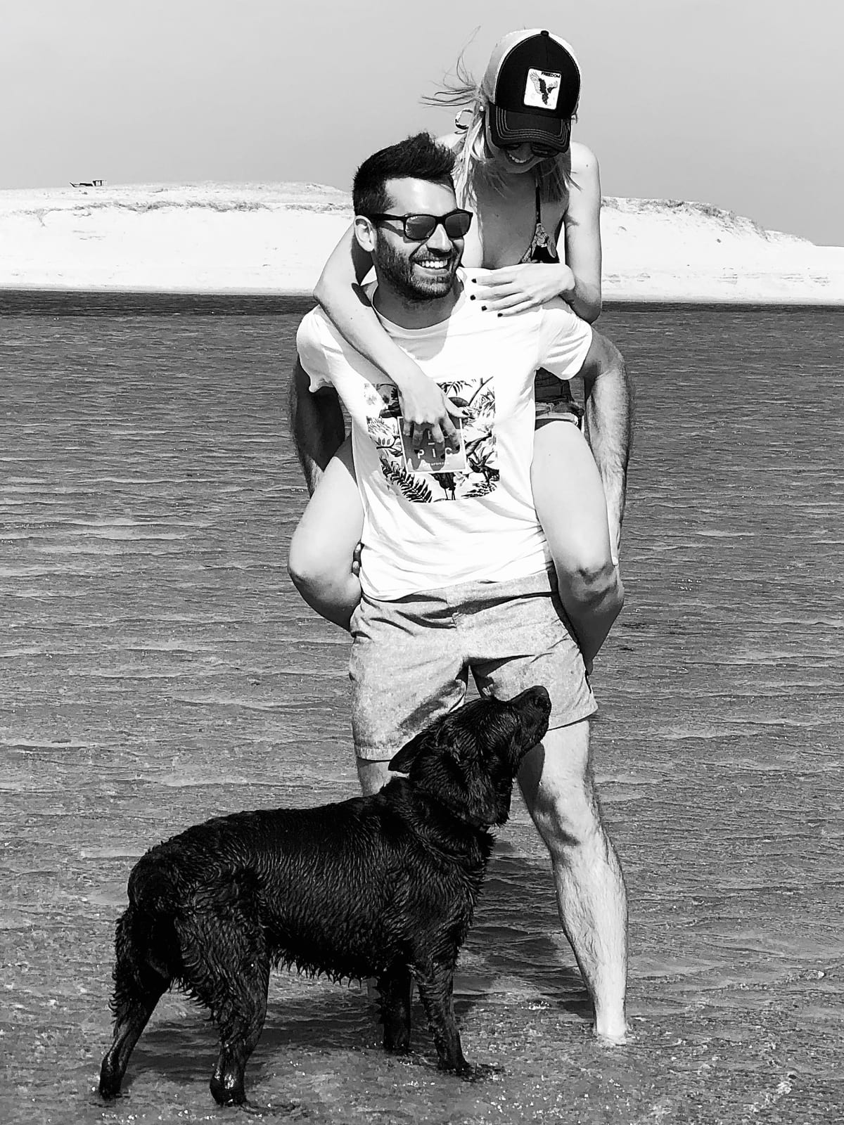 Pablo giving his wife a piggyback ride in the shallow ocean with Lola