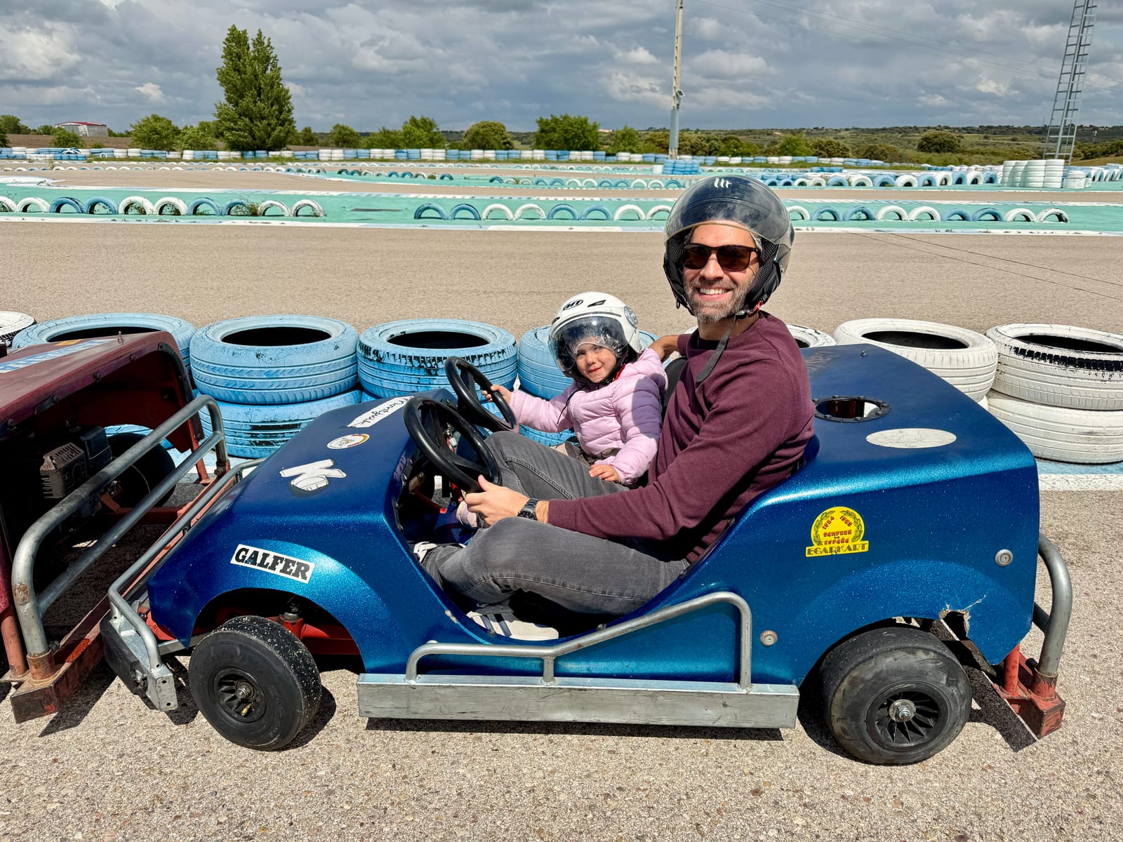 Pablo and his daughter in racing helmets sitting in a go-kart